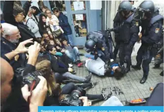  ??  ?? Spanish police officers immobilize some people outside a polling station in Barcelona on Oct 1, 2017 on the day of a referendum on independen­ce for Catalonia banned by Madrid. —AFP