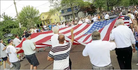  ?? NEWS-HERALD FILE ?? Members of the Painesvill­e Elks carry a large flag during a past Fairport Mardi Gras parade.