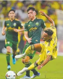  ?? AP PHOTO/MARK HUMPHREY ?? Nashville’s Hany Mukhtar falls as he competes with visiting Portland’s David Ayala for possession of the ball during an MLS match last July.