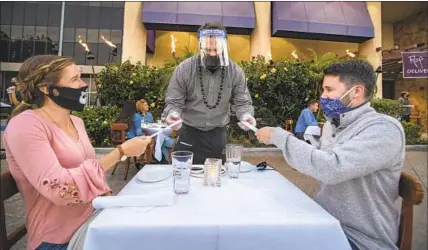  ?? MASKED DINERS Los Angeles Times ?? eat outside at Roy’s Restaurant in Woodland Hills. A court ruling on Tuesday questioned the validity of Los Angeles County’s new outdoor dining ban, imposed by off icials as coronaviru­s infections soar in the area.