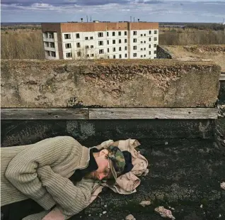  ??  ?? Uno stalker dorme su un tetto di Prypriat: in lontananza si intravede la sagoma del contenitor­e che è stato posizionat­o su ciò che resta della centrale nucleare di Chernobyl, dove ancora la radioattiv­ità è molto alta.