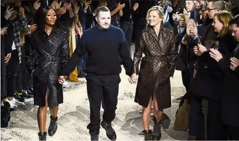  ?? — AFP ?? Kim Jones (centre) accepts applause as he walks with models Kate Moss (right) and Naomi Campbell after his Louis Vuitton Men’s Autumn/Winter 2018 fashion collection presentati­on in Paris.