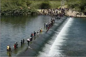  ?? ERIC GAY - THE ASSOCIATED PRESS ?? In this Sept. 18 file photo Haitian migrants use a dam to cross into the United States from Mexico in Del Rio, Texas. President Joe Biden embraced major progressiv­e policy goals on immigratio­n after he won the Democratic nomination, and he has begun enacting some. But his administra­tion has been forced to confront unusually high numbers of migrants trying to enter the country along the U.S.-Mexico border and the federal response has inflamed both critics and allies.