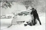  ?? AP FILE PHOTO ?? A man clears snow off of his car from a previous snowstorm.