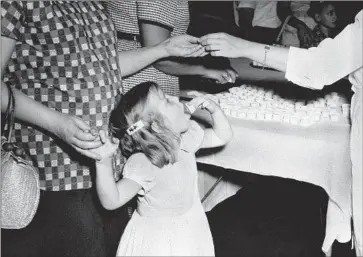  ?? Associated Press ?? A GIRL swallows a lump of sugar coated with polio vaccine, in a photo from July 1962. This summer, New York state researcher­s found evidence of local transmissi­on following a case of paralytic polio in Rockland County.