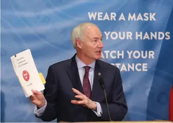  ??  ?? Gov. Asa Hutchinson shows off the vaccine response plan during the weekly COVID-19 press conference on Tuesday, Jan. 12, at the state Capitol in Little Rock.