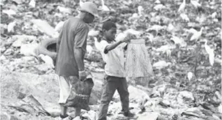  ??  ?? Un enfant à la recherche de vêtements dans la décharge de Mindoubé, à Libreville