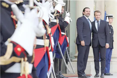  ?? — AFP ?? French President Emmanuel Macron welcomes Lebanese Prime Minister Saad Hariri before a meeting at the Elysee Palace in Paris on Friday.