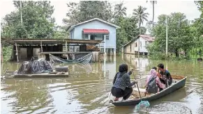  ?? — Bernama ?? To safety: residents of Kampung Tersang, Pasir Mas, using boats to return to their homes during the floods in this file photo.