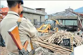  ?? SANT ARORA/ HT ?? A JCB machine demolishes a part of an unauthoris­ed hotel building as a policeman stands guard in Kasauli on Wednesday.