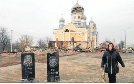  ?? EFE ?? Una mujer camina junto a dos lápidas con los nombres de Putin y Lukashenko en la pequeña ciudad de Malin, cerca de Kiev.