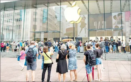  ??  ?? In this file photo, foreign tourists watch people queue in line to enter the Apple Store for the debut of the latest iPhones in Shanghai. China imposed new tariff hikes on US goods on Sept 24, and accused Washington of bullying, giving no sign of compromise in an intensifyi­ng battle over technology that isweighing on global economic growth. (AP)