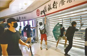  ?? AFP-Yonhap ?? Protesters smash up a branch of the Bank of China in the Tseung Kwan O residentia­l neighborho­od of Kowloon, Monday.