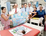 ??  ?? People’s Bank Chairman Sujeewa Rajapakse offering a gift to a newborn baby at the Castle Street Hospital, Borella