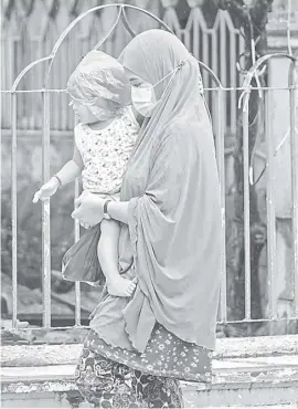  ?? PHOTOGRAPH BY YUMMIE DINGDING FOR THE DAILY TRIBUNE @tribunephl_yumi ?? A MAKESHIFT umbrella is what this Muslim mother used to protect her child from the rain.