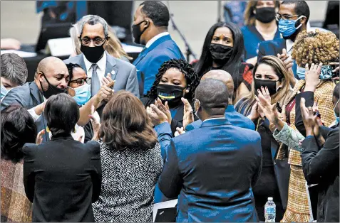  ?? JUSTIN L. FOWLER /THE STATE JOURNAL-REGISTER ?? State Rep. Justin Slaughter, D-Chicago, left, celebrates with lawmakers and staff after the criminal justice reform bill passes in Springfiel­d on Jan. 13.