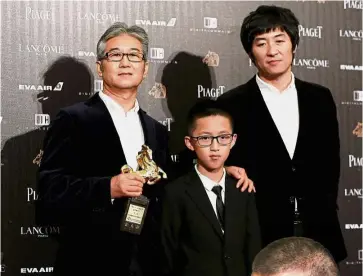  ?? — Reuters ?? Big win: Director Zhang Dalei (right) posing with his father and Kong (centre) after winning the best feature film award for his movie ‘ The Summer is Gone’. (Below) Feng kissing his award for best director.