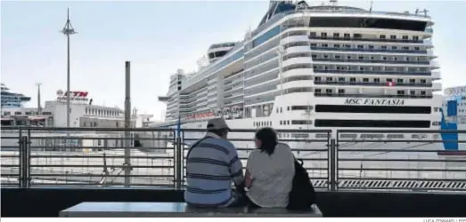  ?? LUCA ZENNARO / EFE ?? Una pareja mira desde un banco un crucero atracado en el puerto de Génova.