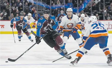  ??  ?? Avalanche center Nathan MacKinnon charges up ice against New York Islanders defenseman Devon Toews last month at the Pepsi Center. MacKinnon leads the Avs and is fifth in the NHL in scoring with 95 points.