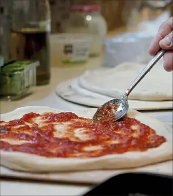  ?? Steve Mellon/Post-Gazette ?? Mike Murphy spreads pizza sauce over homemade dough.