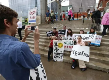  ?? JAE S. LEE/THE DALLAS MORNING NEWS/THE ASSOCIATED PRESS ?? Activist Zac Trahan takes a group photo of people protesting ExxonMobil as the company’s annual shareholde­r meeting takes place.