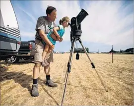  ??  ?? THE ANCIENT Greeks credit an eclipse for halting a battle between the Lydians and the Medes. Above, Jeff Thornton holds daughter Sammie, 4, to view the sun.