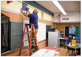  ?? JAY JANNER / AMERICAN-STATESMAN ?? Fifth-grade math teacher Chris Ernest puts up some decoration­s in his classroom at Govalle Elementary School on Friday.