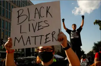  ?? AP Photo/Jacquelyn Martin ?? In this June 24 file photo, Antonio Mingo (right) holds his fists in the air as demonstrat­ors protest in front of a police line on a section of 16th Street that’s been renamed Black Lives Matter Plaza, in Washington.