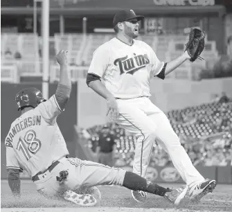  ??  ?? Blue Jays outfielder Curtis Granderson slides home on a passed ball while Twins pitcher Lance Lynn looks on Monday in Minneapoli­s.