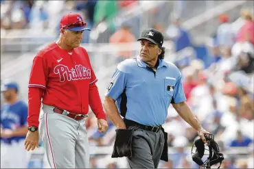  ?? CARLOS OSORIO / AP ?? Philadelph­ia Phillies’ pitching coach Bryan Price walks with umpire Phil Cuzzi during a spring training baseball game March 8 in Dunedin, Fla. Price could end up being the most valuable addition the Phillies made in the offseason if he can get some talented members of the staff to reach their potential.