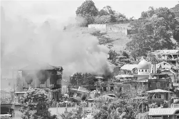  ?? — AFP photo ?? Smoke billows from burning houses after mortar fire, as fighting between government troops and Islamist militants continues, in Marawi on the southern island of Mindanao.