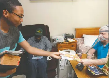  ??  ?? Smiles on faces: Joseph Brice, left, of Meet Me at the Court hands out magazines to Joe Wigner and James Bullock, center, at Courtyard Health and Rehabilita­tion Saturday.