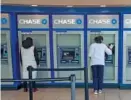  ?? AP PHOTO/MARY ALTAFFER ?? A Chase bank employee, right, cleans the branch’s ATMs as a customer uses another in 2020 in the Flushing neighborho­od of the Queens borough of New York.