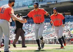  ?? Associated Press ?? Houston Astros' Evan Gattis, left, congratula­tes Carlos Correa as he and George Springer, right, score on Correa's two-run home run off Minnesota Twins pitcher Hector Santiago in the first inning of a baseball game Wednesday in Minneapoli­s.