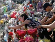  ?? AP PHOTO BY JOHN LOCHER ?? A woman leans over to write a message on a cross at a makeshift memorial at the scene of a mass shooting at a shopping complex, Tuesday, Aug. 6, 2019, in El Paso, Texas.