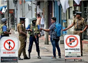  ?? AP ?? Lankan policemen check the identity card of a person carrying a backpack in Colombo on Monday. —