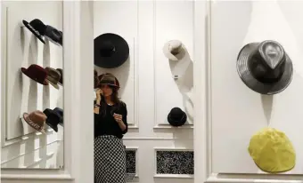  ?? AP PHOTOS ?? MASS APPEAL: A woman tries on one of many hats on display at a Borsalino shop in downtown Milan, Italy. The hat-maker is taking steps to add a couture cachet to its venerable and distinctiv­e brand.