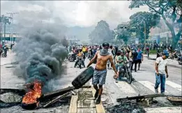  ?? RONALDO SCHEMIDT/GETTY-AFP ?? Anti-government activists lash out Sunday in Valencia, site of a Venezuela military base.