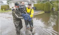  ?? RYAN REMIORZ/THE CANADIAN PRESS ?? Officers carry Nadia Makhavekov­a to a boat so she can get some belongings from her flooded home on Friday.