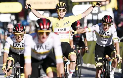  ?? — AFP photo ?? Pogacar (centre) wearing the overall leader’s yellow jersey celebrates with his teammates as he crosses the finish line at the end of the 21th and last stage of the 108th edition of the Tour de France cycling race, 108 km between Chatou and Paris Champs-Elysees.