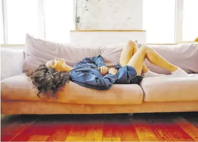  ?? EL PERIÓDICO ?? Una joven, tumbada en el sofá, por sus dolores menstruale­s.