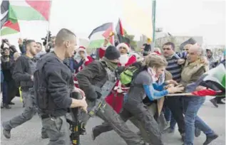  ??  ?? BETHLEHEM: Israeli border police officers scuffle with Palestinia­n protesters, some are dressed as Santa Claus, during a protest in front of an Israeli checkpoint, in the West Bank city of Bethlehem yesterday.—AP
Israel turns to Trump