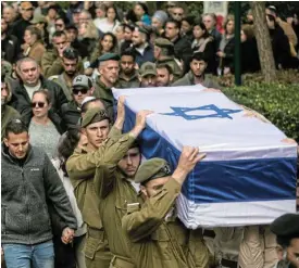  ?? /Amir Levy/Getty Images ?? Killed in action: Family and friends mourn as they walk behind the coffin during the funeral of Sgt-Maj Matan Lazar.