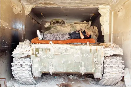  ??  ?? An anti-Assad fighter rests on a tank in in Deraa, Syria, on Friday. (Reuters)