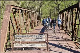  ?? Arkansas Democrat-Gazette/MICHAEL STOREY ?? Walkers cross the old iron bridge at the southern trailhead of Clarksvill­e’s Spadra Creek Nature Trail.