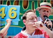 ?? AP PHOTO BY BEBETO MATTHEWS ?? Joey Chestnut eats two hot dogs at a time during the Nathan’s Annual Famous Internatio­nal Hot Dog Eating Contest, Tuesday in New York. Chestnut won, marking his 10th victory in the event.