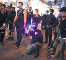  ?? CHINA DAILY ?? A protester points a high-power laser at police officers during an illegal rally in Tsim Sha Tsui, Hong Kong on Saturday night, while some protesters wearing black protective glasses stand beside him.