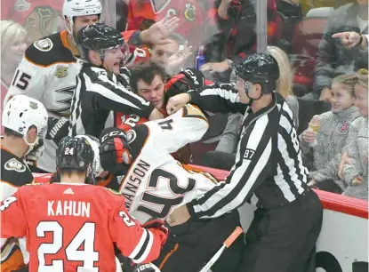 ?? MATT MARTON/AP ?? Blackhawks wing Alex DeBrincat (12, against the glass) and Ducks defenseman Josh Manson scuffle during the second period Tuesday at the United Center. Both were penalized for roughing.