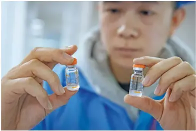  ??  ?? ▴ The production chain uses digital technology to strictly monitor every step of production and packaging.
▶ A staff member shows finished vaccines filled in the vial.