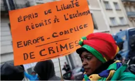  ??  ?? A woman holds a placard as she attends a protest against slavery outside the Libyan embassy in Paris. Photograph: Philippe Wojazer/Reuters